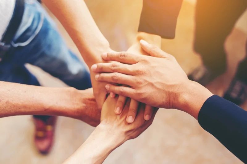 Mãos de vários voluntários empilhadas umas sobre as outras em sinal de união